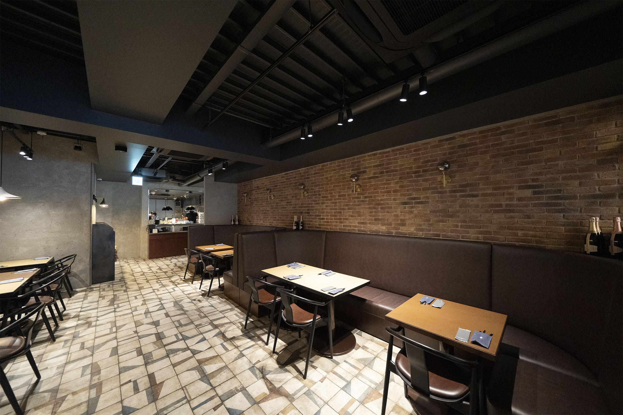 Journal Standard DINING 新宿店の客席。ソファ席の壁一面にブリックタイル CAN'BRICK ネザーランド（NL-6）、床に幾何学柄タイル BOTTEGA（PLAY）を施工した内装